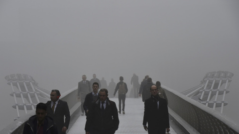 Trabajadores de la ciudad cruzan la pasarela del Milenio sobre el río Támesis entre la niebla.- REUTERS.