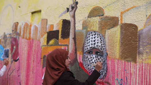 Una mujer palestina pinta un mural en protesta por los ataques israelíes en Rafah al sur de la Franja de Gaza. /REUTERS