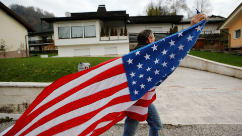 Un hombre ondea una bandera de Estados Unidos delante de la casa de los padres de Melania Trump. / SRDJAN ZIVULOVIC Un hombre ondea una bandera de Estados Unidos delante de la casa de los padres de Melania Trump. / SRDJAN ZIVULOVIC