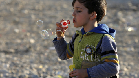 Un niño inmigrante hace pompas de jabón mientras espera a su traslado a un campo de tránsito en Gevgelija, Macedonia, después de entrar en el país por el cruce de la frontera con Grecia, 4 de noviembre de 2015. REUTERS / Ognen Teofilvovski