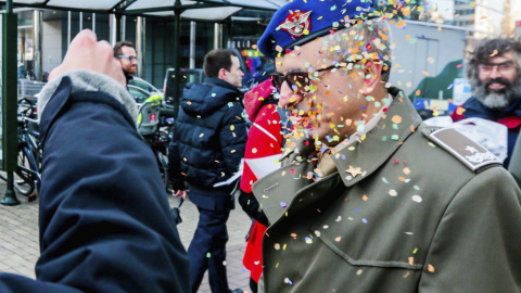 Un activista arroja confeti a un soldado delante de la sede de la Comisión Europea para protestar contra las subvenciones europeas a la industria armamentística en Bruselas (Bélgica). EFE/Stephanie Lecocq