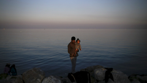 Un refugiado sirio sostiene un bebé en el puerto de Mitilene , en la isla griega de Lesbos. REUTERS