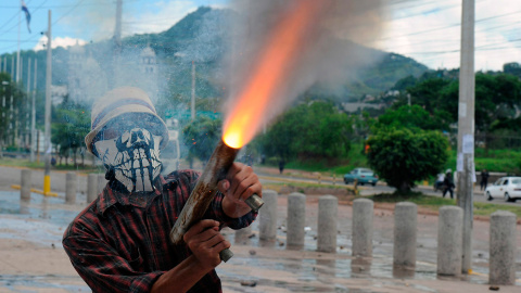 Un estudiante de la Universidad Nacional Autónoma de Honduras (UNAH) dispara un arma casera durante los enfrentamientos con la policía.- ORLANDO SIERRA (AFP)
