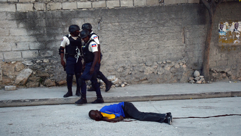 Policias haitianos caminan junto a un partidario del candidato presidencial Jean Charles Moise, disparado durante una manifestación en Port-au-Prince.- HECTOR RETAMAL (AFP)