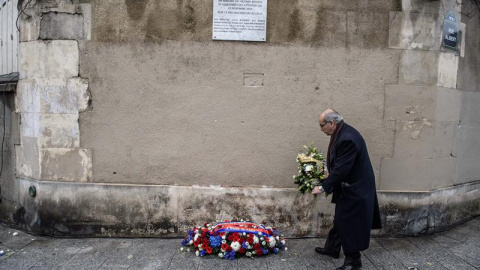 Un hombre deja un ramo de flores ante una placa conmemorativa de los atentados de hace un año./ EFE