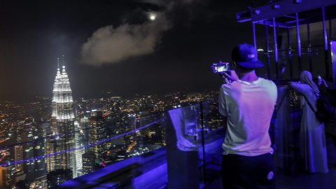 Un turista toma una fotografía de la superluna en la Torre de Kuala Lumpur en Kuala Lumpur (Malasia). EFE/Ahmad Yusni