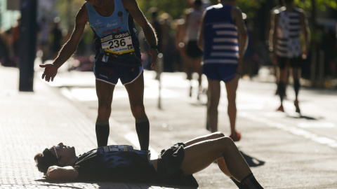Un atleta descansa sobre la acera tras atravesar la línea de meta, durante la 51 edición de la carrera popular Behobia-San Sebastián, en la que participan 34.000 personas. EFE/Juan Herrero