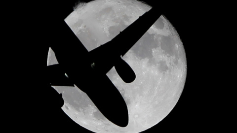 Un avión de pasajeros surca el cielo frente a la superluna en España. REUTERS/Jon Nazca