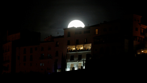 Un grupo de personas se asoma a un balcón mientras la Superluna se alza tras ellos en Ronda. REUTERS/Jon Nazca