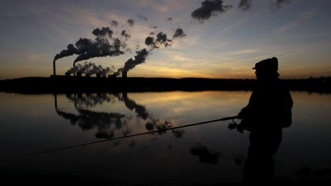 Un hombre pesca en un lago artificial fuera de la central eléctrica Belchatow, en Polonia. REUTERS