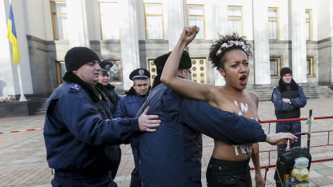 Un policía ucraniano arresta a una activista del movimiento Femen durante una protesta delante del Parlamento en Kiev (Ucrania) contra la homofobia y para reclamar que se corrija el Códido Laboral del país para prevenir y actuar contra la d