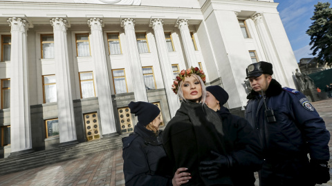 Un policía ucraniano arresta a una activista del movimiento Femen durante una protesta delante del Parlamento en Kiev (Ucrania) contra la homofobia y para reclamar que se corrija el Códido Laboral del país para prevenir y actuar contra la d