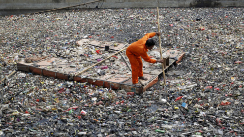Un trabajador limpia los escombros flotando en el río frente a la temporada de lluvias en el norte de Yakarta, en Indonesia. REUTERS/Garry Lotulung.