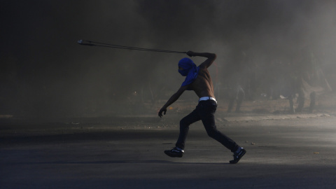 Un joven palestino lanza piedras contra soldados israelíes durante una protesta en Beit El, a las afueras de la ciudad cisjordana de Ramala. EFE/ALAA BADARNEH