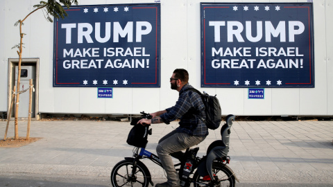 Un hombre montado en bicicleta pasa junto a unos letreros en Tel Aviv parafraseando el lema de campala de Donadl Trump. REUTERS/Baz Ratner Un hombre montado en bicicleta pasa junto a unos letreros en Tel Aviv parafraseando el lema de campala de Donadl Trump. REUTERS/Baz Ratner