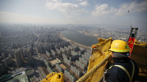 Un albañil observa las vistas desde la planta 99 de la torre Lotte World en Seúl, que actualmente se encuentra en construcción. / REUTERSUn albañil observa las vistas desde la planta 99 de la torre Lotte World en Seúl, que actualmente se en