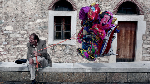 Un hombre vende globos en una plaza de Atenas. / AFP