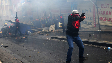 Un hombre apunta su arma frente a la policía durante los disturbios del pasado 11 de Marzo en Estambul. / AFP
