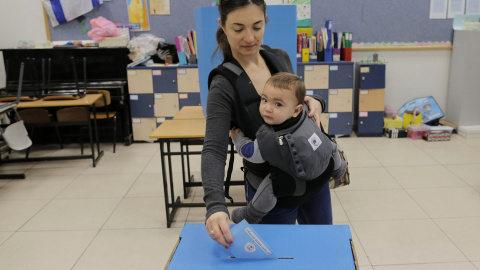 Una mujer emite su voto junto a su bebé en las elecciones parlamentarias en un colegio electoral en la ciudad norteña de Haifa, Israel./ REUTERS