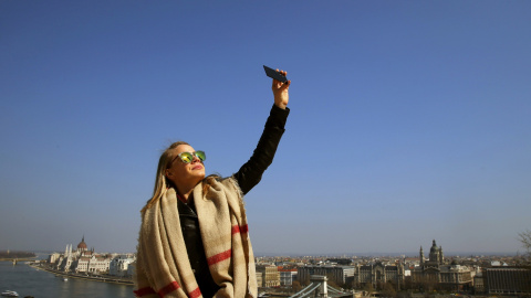 Una mujer en Budapest (Hungría) trata de ver el eclipse parcial de sol a través de un cristal oscuro. REUTERS/Laszlo Balogh