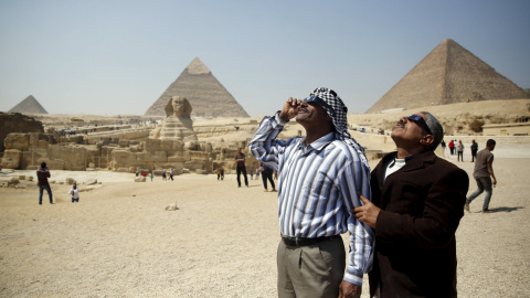 Dos personas observan el eclipse parcial de sol junto a las piramides, en El Cairo. REUTERS/Amr Abdallah Dalsh