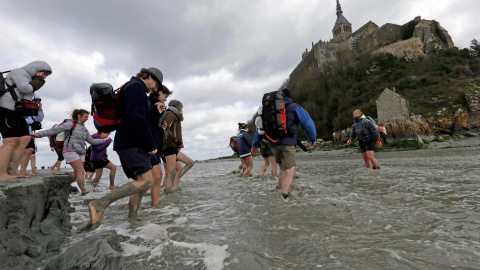 El guía Sebastien Daligault acompaña a un grupo de visitantes con el agua hasta las rodillas durante un recorrido a pie por hasta el Mont Saint-Michel, en la costa francesa de Normandía. REUTERS / Pascal Rossignol