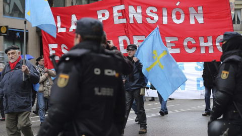 Participantes en las Marchas por la Dignidad pasan ante varios policiales en la Plaza de Colón, donde han confluido las nueve columnas procedentes de todas las comunidades autónomas. EFE/Ballesteros