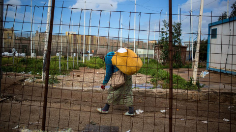 Una mujer trata de cruzar la valla cargada con varios paquetes. - JAIRO VARGAS