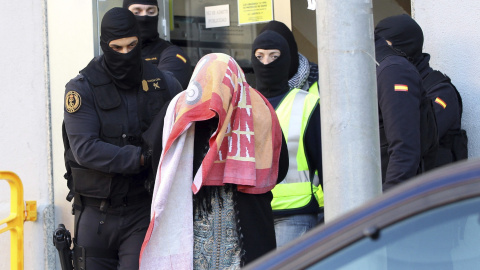 Agentes de la Guardia Civil escoltan a la mujer que, junto a su marido y a sus dos hijos gemelos, han sido detenidos en Badalona por la Guardia Civil por su presunta relación con una red de envío de yihadistas a Siria. EFE/Toni Garriga