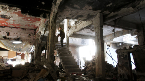 Un combatiente toma posición en las escaleras de un edificio destrozado por los bombardeos en Yarmuk. - YOUSSEF KARWASHAN / AFP Un combatiente toma posición en las escaleras de un edificio destrozado por los bombardeos en Yarmuk. - YOUSSEF KARWASHAN / AFP