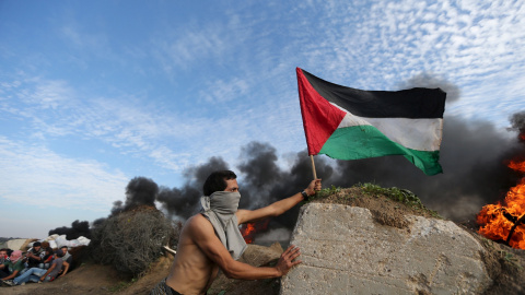 Un manifestante coloca una bandera palestina durante los enfrentamientos con las tropas israelíes cerca de la frontera entre Israel y el centro de la Franja de Gaza. REUTERS/Ibraheem Abu Mustafa