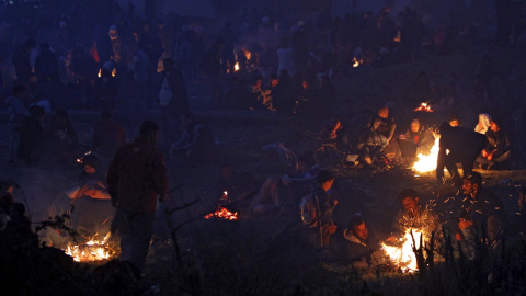 Refugiados junto a las hogueras mientras esperan para entrar en un campo de registro después de cruzar la frontera de Grecia en Gevgelija, Macedonia. REUTERS/Ognen Teofilovski