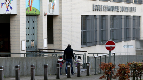 Un hombre vuelve a casa con sus hijos tras descubrir que la escuela estaba cerrada por el riesgo de atentados que hay en la capital belga.- REUTERS.