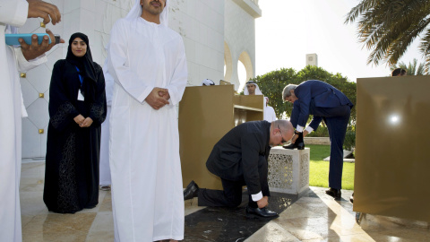 El Ministro de Exteriores de Emiratos Árabes Unidos, Abdullah bin Zayed Al Nahyan espera al secretario de Estado estadounidense, John Kerry, y un miembro de seguridad mientras se atan los cordones de los zapatos después de recorrer la Gran 
