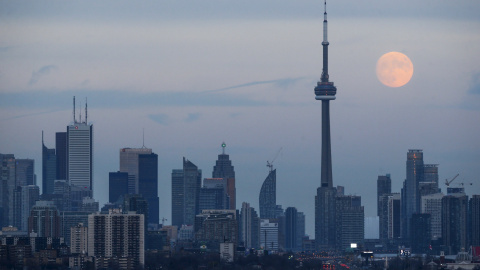 La luna se deja ver detrás de la Torre Nacional de Canadá, un punto de referencia del país. REUTERS / Marcos Blinch