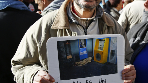 Un hombre enseña una foto de una casa con la frase "Esto no es un hogar", en la protesta convocada por la plataforma "nadie sin hogar" en las calles de Madrid, 26 de noviembre de economía 2015. REUTERS / Paul Hanna