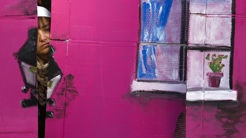 Una manifestante se asoma por detrás de una casa de cartón en la protesta convocada por la plataforma "Nadie Sin Hogar" en Madrid, España, 26 de noviembre de economía 2015. REUTERS / Paul Hanna