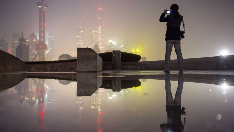 Un hombre saca una foto de la zona financiera del Nuevo Distrito de Pudong que está cubierta por una nube de contaminación. Shangai, China. REUTERS/Stringer