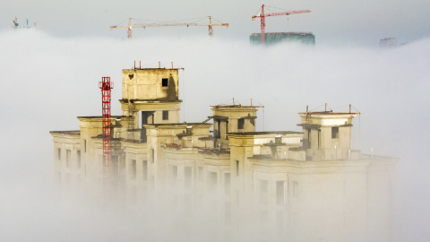 Grúas y edificios residenciales en construcción se ven entre una espesa niebla en Anyang, China. REUTERS/Stringer