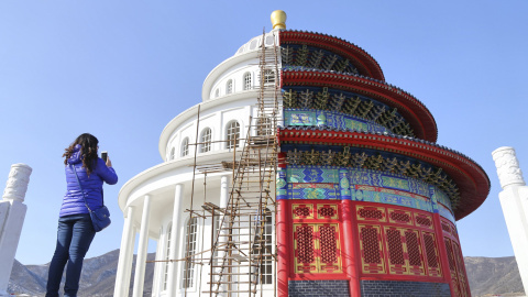 Una mujer fotografía un templo que se divide en dos partes: una parte representa la entrada del templo de Heaven y la otra mitad, un estudio de producciones de cine típicas del occidente. Provincia de Hebei, China. REUTERS/Stringer