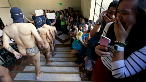 Unos estudiantes filipinos se ruborizan al ver el 'desfile' de Alpha Phi Omega, una fraternidad que camina desnuda durante la Ofrenda del Año en la Universidad de Manila, Filipinas. REUTERS/Romeo Ranoco