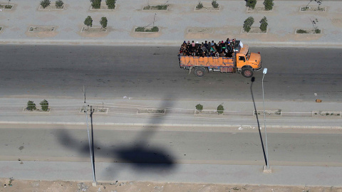 Una fotografía aérea muestra la sombra de un helicóptero de las fuerzas de seguridad iraquíes, mientras un camión transporta peregrinos musulmanes chiítas, en la ciudad de Kerbala, a unos 120 kilómetros de Bagdad.- MOHAMMED SAWAF (AFP)