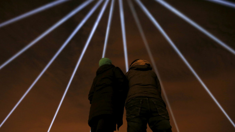 Una pareja observa los rayos de luz azules que son proyectados durante una vigilia para recordar a las víctimas del tiroteo masivo de Quebec, Canadá. REUTERS/Christinne Muschi