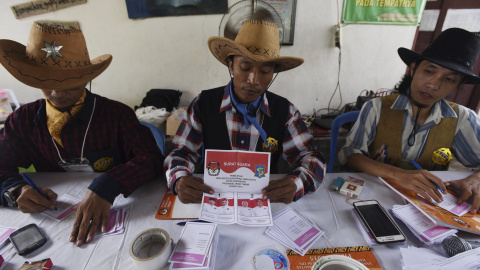 Miembros de mesa vestidos con trajes de vaquero preparan papeletas en un colegio electoral en Surabaya, en Indonesia. REUTERS