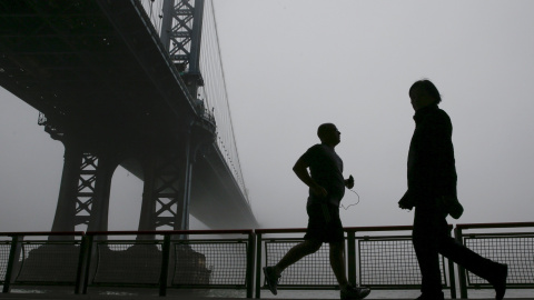 Siluetas de personas haciendo ejercicio en el Puente de Manhattan cubierto por la niebla en Nueva York. REUTERS/Shannon Stapleton