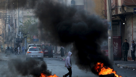 Un niño camina entre neumáticos en llamas durante una protesta contra el toque de queda en el distrito Sur, en la ciudad suroriental de Diyarbakir, Turquía. REUTERS/Sertac Kayar