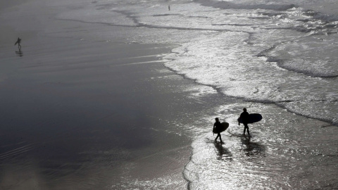 Unos surfistas se dirigen al mar para practicar una sesión de entrenamiento en este inusual cálido invierno francés. REUTERS/Regis Duvignau