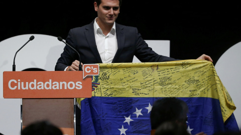 El líder de Ciudadanos, Albert Rivera, sostiene una bandera venezolana firmada durante el cierre de campaña para las elecciones del 20-D en Madrid. REUTERS/Andrea Comas