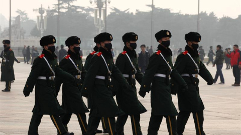Miembros de las fuerzas de seguridad paramilitares chinas patrullan la ciudad de Pekín, ataviados con máscaras para protegerse de la polución. En la capital china, la alerta roja por contaminación implica restricciones severas al tráfico (c