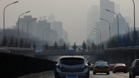 Un vehículo circula por una vía de entrada a Pekín (China), ciudad oculta por espesa niebla de polución. Las autoridades recomiendan a los ciudadanos que reduzcan sus actividades en el exterior y se espera que se suspendan las clases en gua